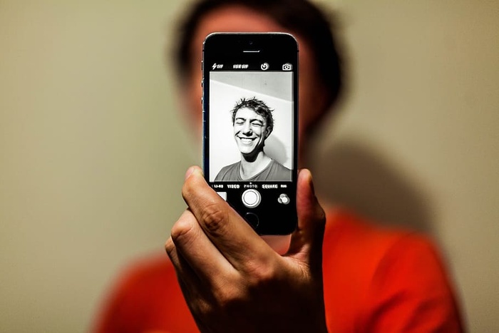 身穿红衫的男子在Iphone上以灰度模式自拍