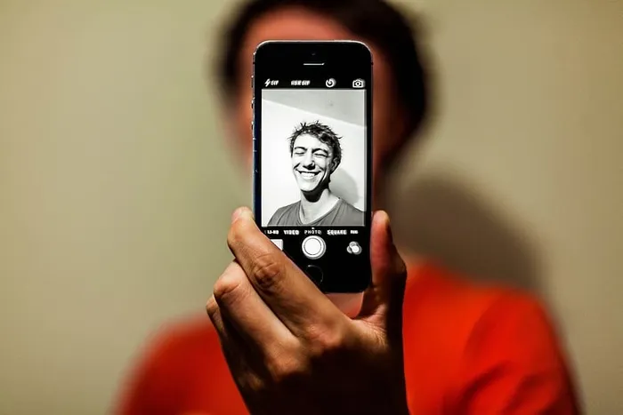 身穿红衫的男子在Iphone上以灰度模式自拍