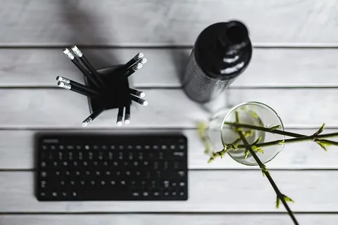 白色桌子上带铅笔的黑色键盘