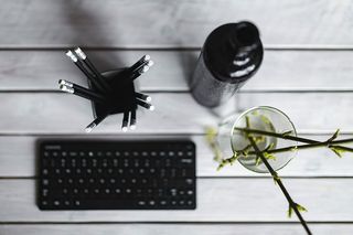 白色桌子上带铅笔的黑色键盘