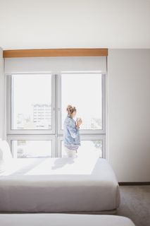 在空床附近的玻璃窗上观看的女人