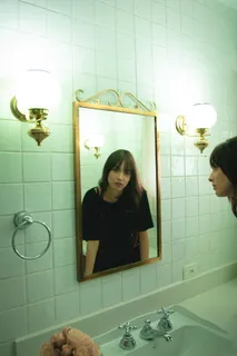 穿着黑色T恤的女人盯着墙上的镜子 穿着黑色T恤的女人盯着墙上的镜子