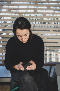 坐在长凳上使用智能手机的女子