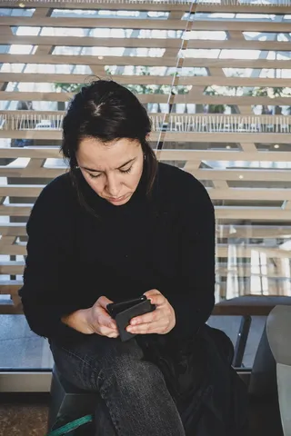 坐在长凳上使用智能手机的女子