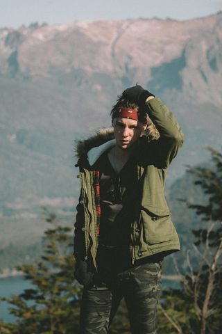 白天穿着绿色派克大衣的男人站在山上