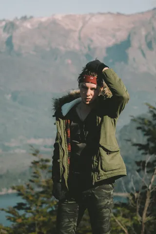 白天穿着绿色派克大衣的男人站在山上