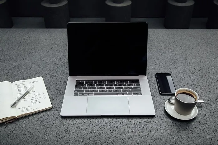 在一杯咖啡、iPhone、笔记本和钢笔之间关闭MacBook Pro