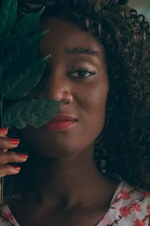 一名女子举着绿叶遮住眼睛的特写照片