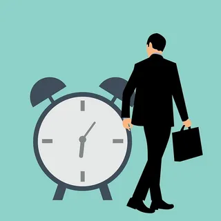 商人拿着公文包走过闹钟的插图。 商人拿着公文包走过闹钟的插图。