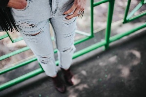 穿着黑色夹克和绿色扶手撕破牛仔裤的金发女人