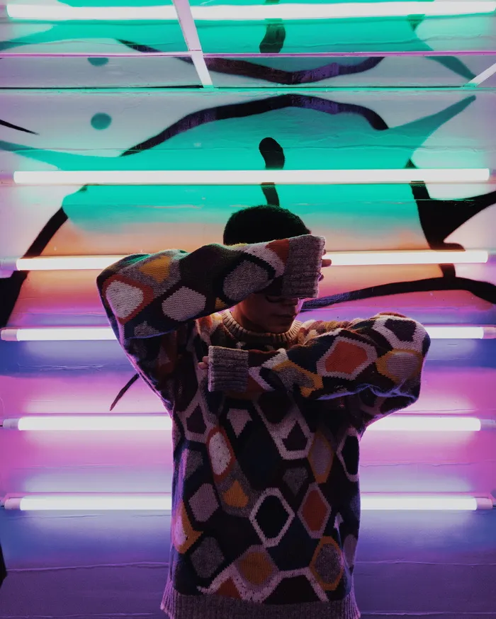 一名男子站在荧光灯旁捂住脸