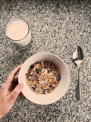 一个圆形的白色陶瓷碗，里面放着燕麦粥，旁边放着一杯牛奶