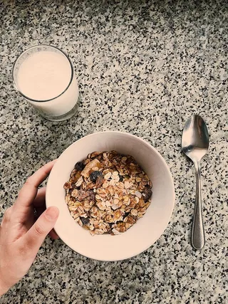 一个圆形的白色陶瓷碗，里面放着燕麦粥，旁边放着一杯牛奶