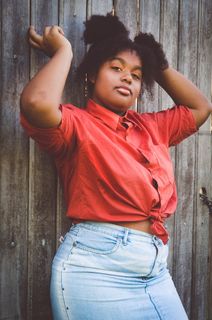 一名女子举起双臂，靠在木栅栏上