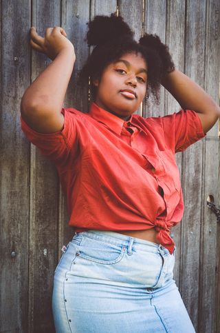 一名女子举起双臂，靠在木栅栏上