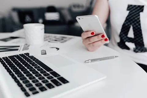 女商人在办公桌前使用手机 女商人在办公桌前使用手机