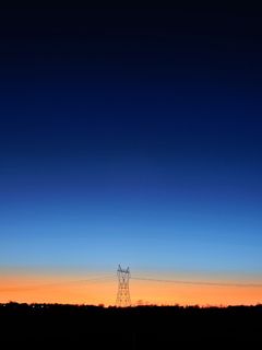 蓝色和橙色天空下的黑色发射塔