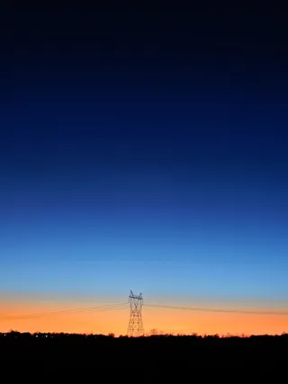 蓝色和橙色天空下的黑色发射塔