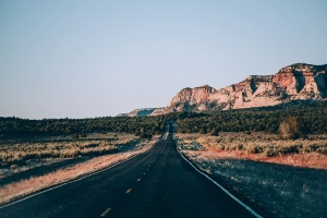 一条美国沙漠公路，背景为多岩石的层状山脉