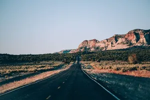 一条美国沙漠公路，背景为多岩石的层状山脉