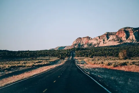 一条美国沙漠公路,背景为多岩石的层状山脉 一条美国沙漠公路,背景为多岩石的层状山脉