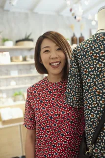 微笑的女人站在展示的衬衫旁边 微笑的女人站在展示的衬衫旁边