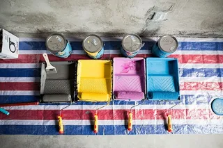 容器和油漆辊旁边有四个各色油漆罐