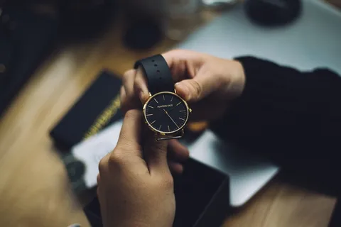 拿着黑色表带的金色模拟表的人 拿着黑色表带的金色模拟表的人