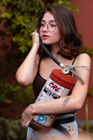 身穿黑色意大利面束带上衣、手持灭火器的女子