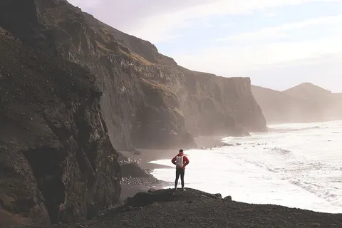 一个徒步旅行者站在引人注目的冰岛海岸上 一个徒步旅行者站在引人注目的冰岛海岸上