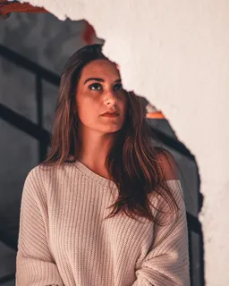 破碎的白墙附近一名女子的特写照片