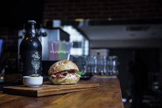 汉堡包放在砧板上，靠近陶瓷碗和玻璃瓶