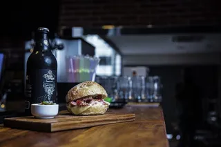 汉堡包放在砧板上，靠近陶瓷碗和玻璃瓶