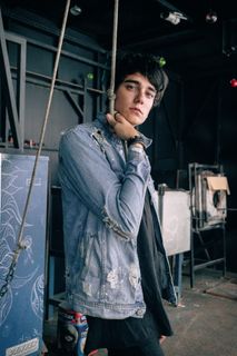 男子穿着牛仔夹克，手持绳索