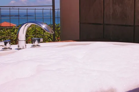 房间内棕色墙面附近的灰色龙头下，浴缸上有白色肥皂泡沫