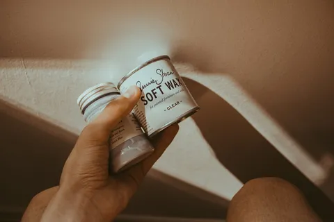 拿着带有白色标签罐的软蜡罐的人 拿着带有白色标签罐的软蜡罐的人