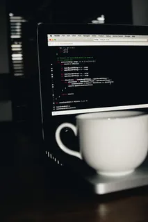 在MacBook Pro上打开白色陶瓷茶杯的照片