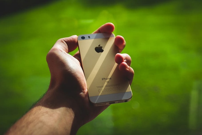 手持银色Iphone 5s的人