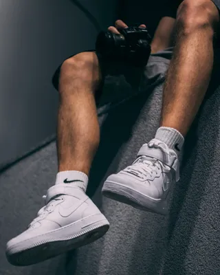 坐在灰色人行道上拿着黑色单反相机的男子