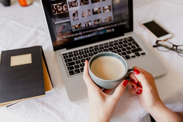 一位女士在一张桌子旁工作，桌上有一台笔记本电脑和一杯咖啡