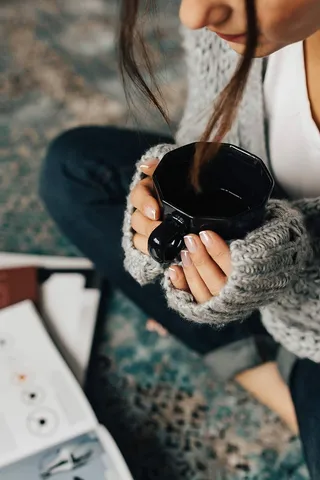 女人一边喝茶一边在地上看杂志