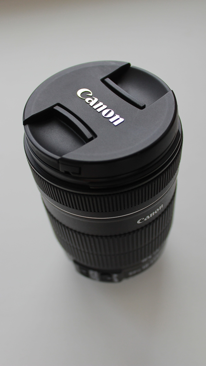 白色桌面上的黑色佳能 DSLR 相机镜头