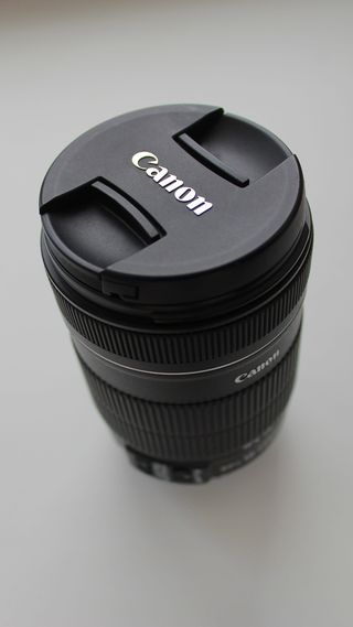 白色桌面上的黑色佳能 DSLR 相机镜头