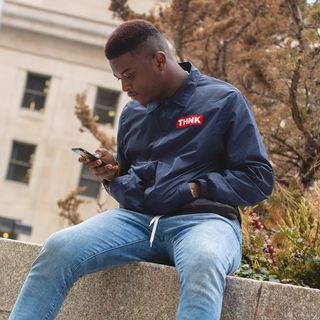 白天，一名男子坐在树旁的混凝土砌块上