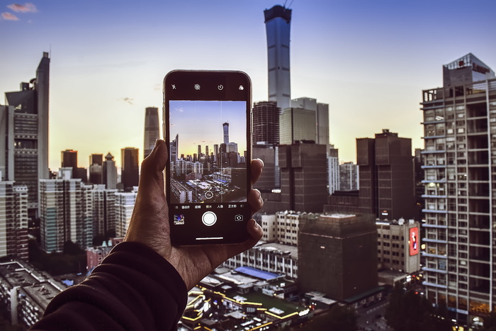 手持智能手机拍摄高层建筑的人