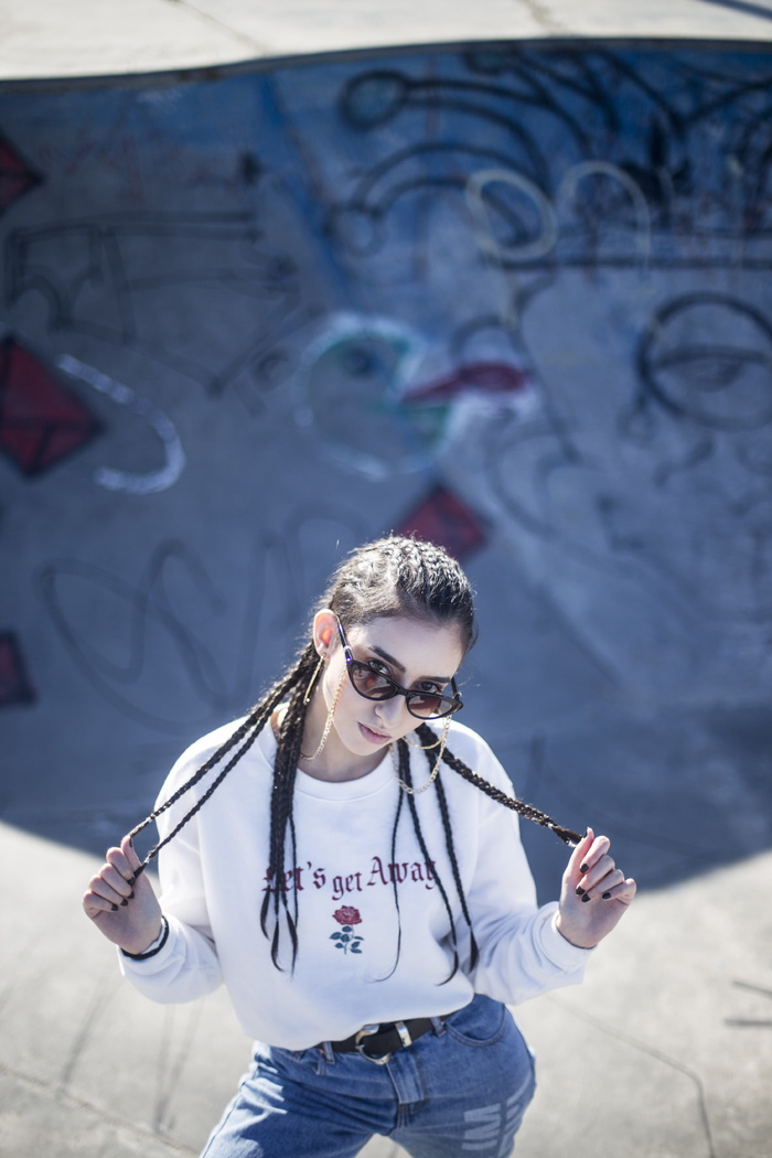 身穿白色长袖衬衫的女子手持辫子，站在溜冰场内的照片
