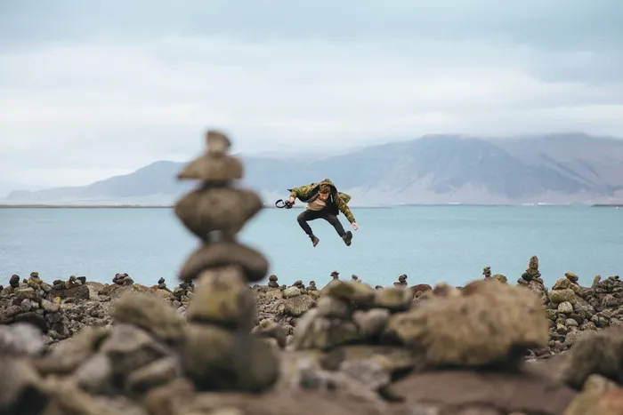 一个年轻的高加索徒步旅行者在一个山湖的石头海岸上