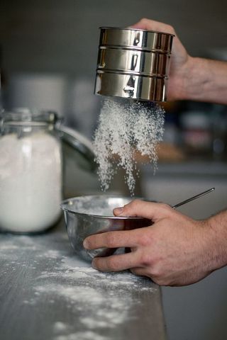 在碗上撒白色粉末的人