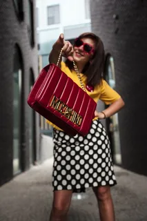 身穿黄色圆领T恤，手持红色手提包的女子