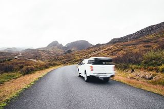 模糊的皮卡车在公路上行驶，背景是山脉